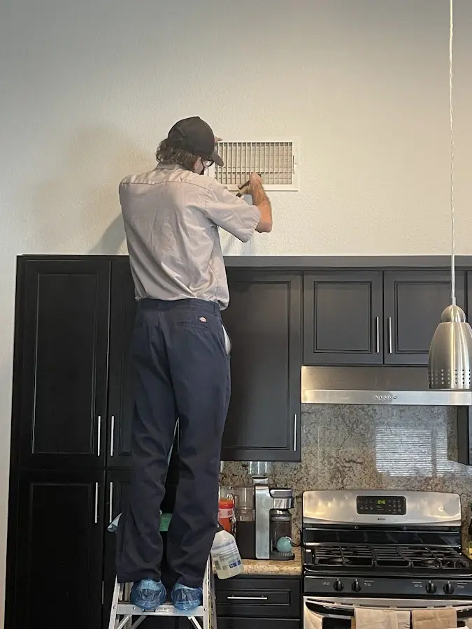 Technician inspecting an air vent during HVAC service in Aledo